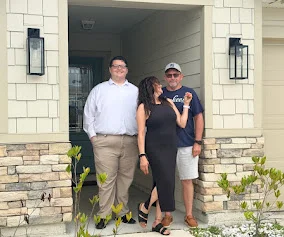 Stone Merton with clients in front of their new home