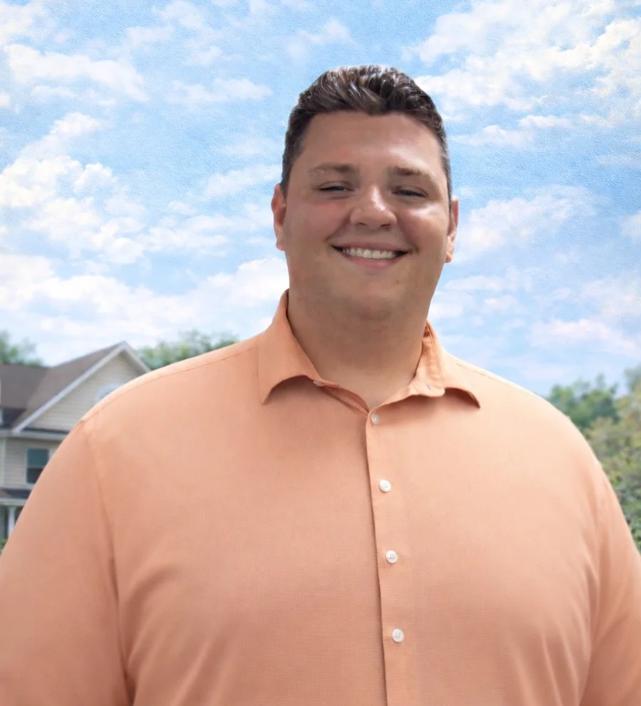 Stone Merton, mortgage loan officer, smiling in front of a home